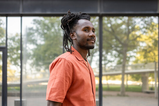 Cuban man in orange shirt standing by glass building