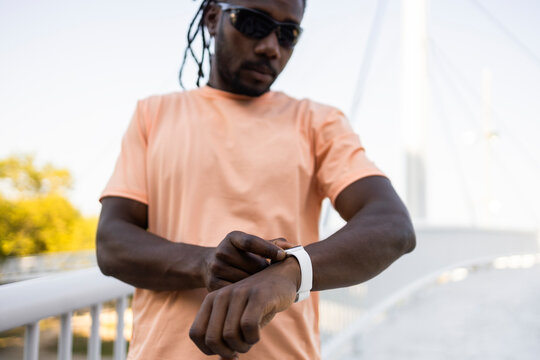 Cuban athlete checking smartwatch outdoors on sunny day
