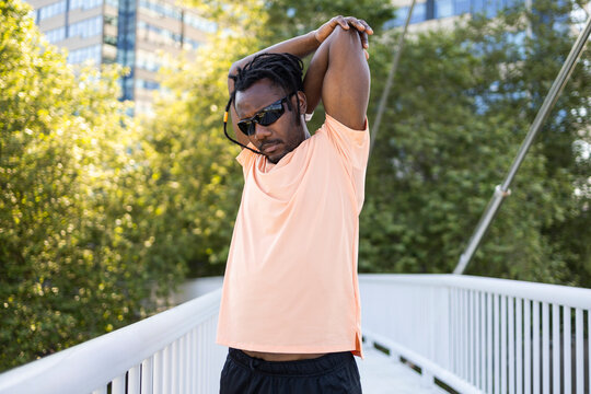 Cuban man stretching outdoors on city bridge in summer