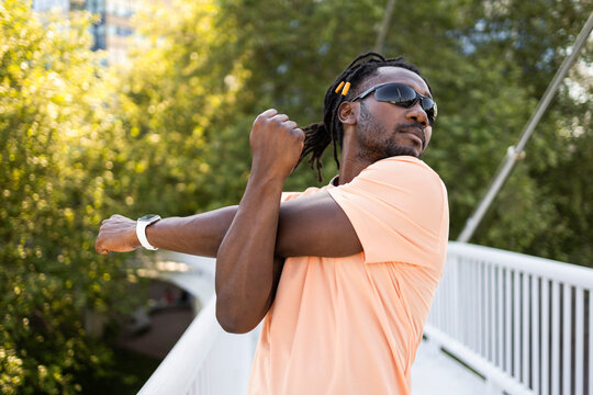 Cuban man stretching outdoors on a sunny urban bridge