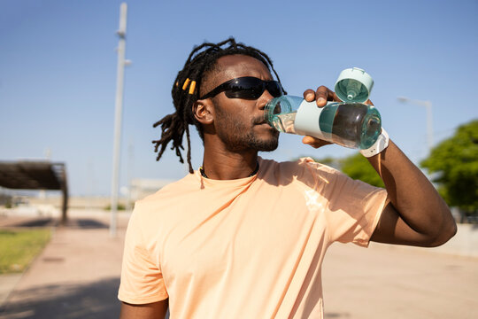 Cuban man hydrating after workout outdoors in sunlight