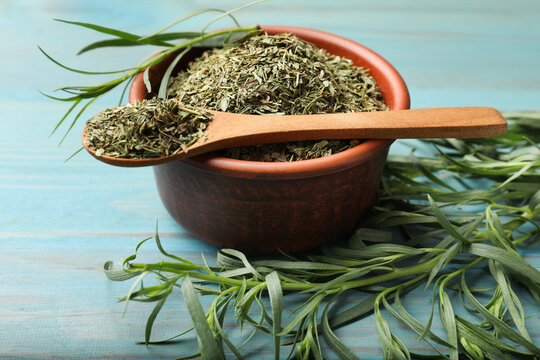 Dry tarragon and fresh leaves on light blue wooden table, closeup