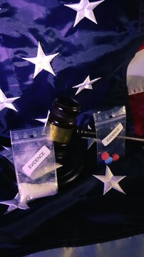 Dramatic representation of drug related crime in America, with a judge's gavel and evidence bags containing narcotics and pills placed on the United States flag, symbolizing the national issue