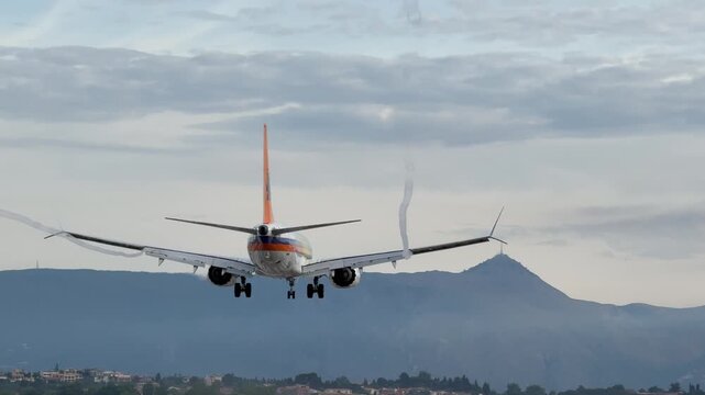 Jet aircraft lands at Nice Cote d'Azur Airport with mountains in background