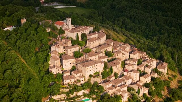Labro village Rieti Italy aerial 70mm drone view of medieval hilltop borgo in sunset golden hour, dense forest green hills landscape tilt up movement. Hidden gems of central Italy