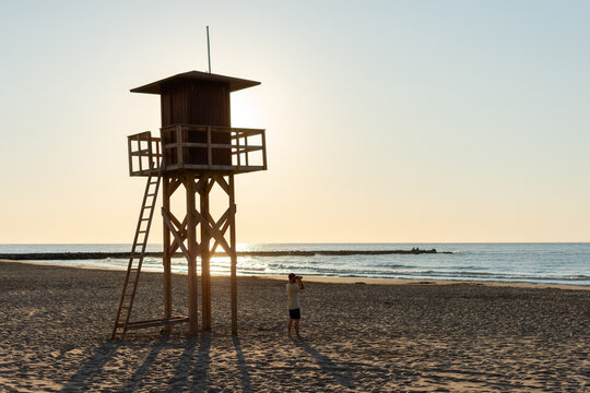 Lifeguard tower and man with binoculars watching the sea