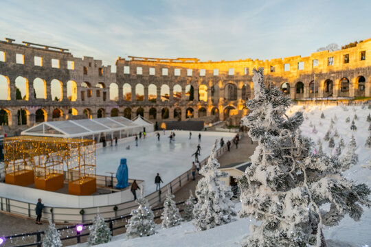 Ice skating rink inside the Roman Amphitheater in Pula, Croatia during Christmas season. Concept of festive atmosphere, winter holidays and cultural tourism