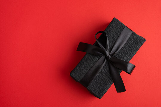 Black gift box creating elegant surprise on red background