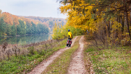 Obraz premium Autumn landscape, panorama, banner - the road with cyclist near lake in the sunny day