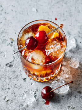 classic manhattan cocktail on the rocks with cherry and orange twist garnish