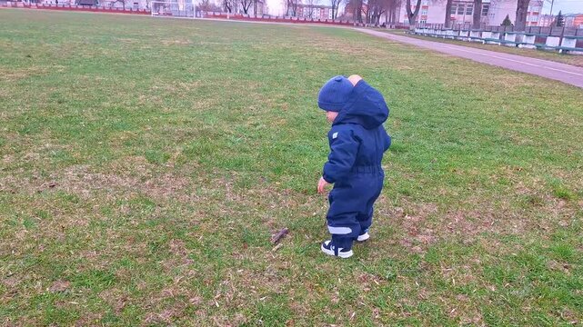 Toddler in jumpsuit taking first steps on grass