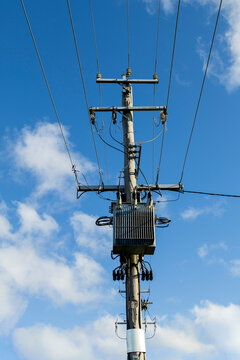 Electricity pole and wires set against blue sky