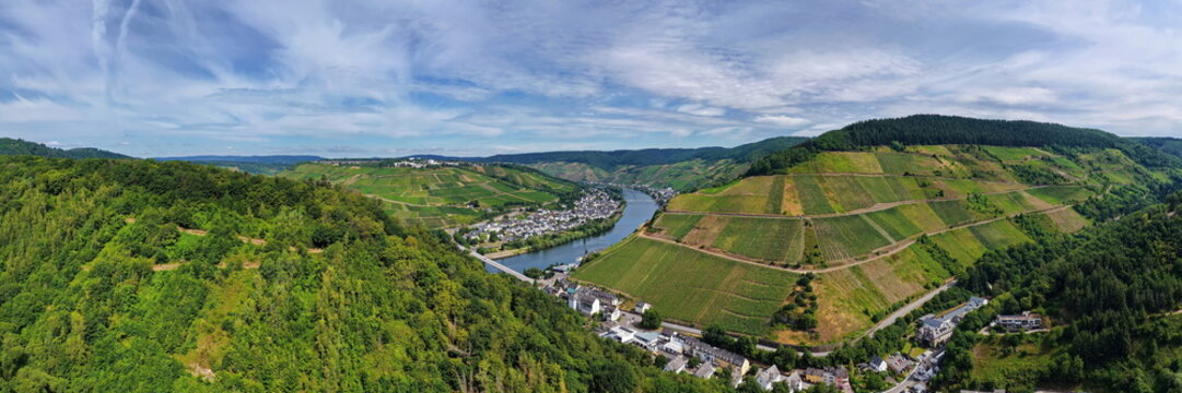 Luftaufnahme der Moselschleife bei Zell mit steilen Weinbergen, charakteristischen Schieferd&auml;chern, Br&uuml;cken und dem Flussverlauf an einem sonnigen Sommertag in Rheinland-Pfalz.