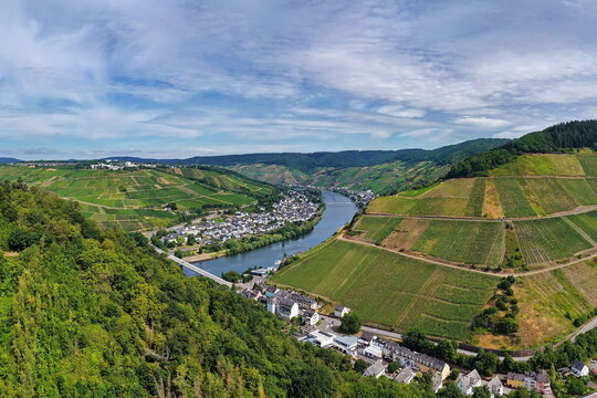 Luftaufnahme der Moselschleife bei Zell mit steilen Weinbergen, charakteristischen Schieferd&auml;chern, Br&uuml;cken und dem Flussverlauf an einem sonnigen Sommertag in Rheinland-Pfalz.