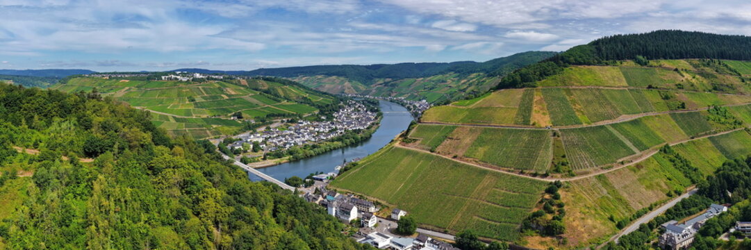 Luftaufnahme der Moselschleife bei Zell mit steilen Weinbergen, charakteristischen Schieferd&auml;chern, Br&uuml;cken und dem Flussverlauf an einem sonnigen Sommertag in Rheinland-Pfalz.
