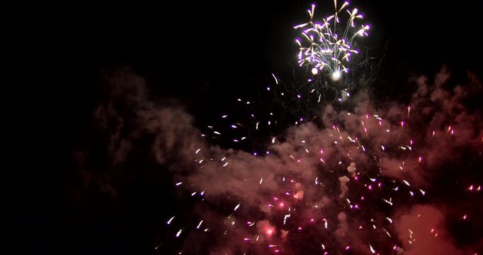 Red And Blue Fireworks Exploding In Night Sky On Day Of Celebration While Leaving Smoke Behind