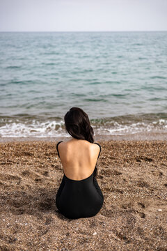 Woman sitting on a beach gazing at the sea