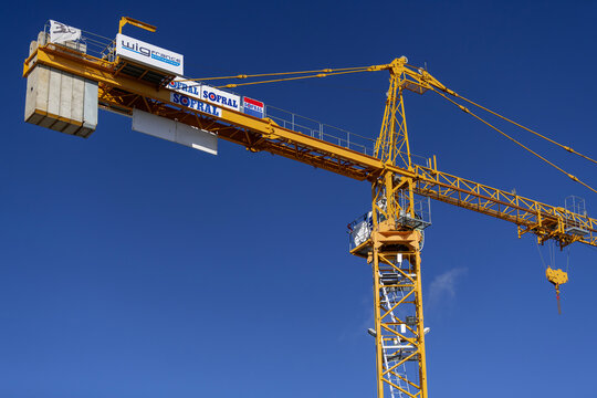 Nancy, France - October 4th 2020 : View on a yellow hammerhead top-slewing tower crane Potain MD 265 B1 J10 on a construction site for the construction of a building with the blue sky.