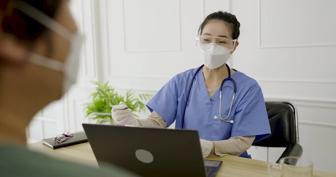 Portrait of asian woman doctor wear protection face mask showing a patient on digital tablet clip board, patient listen to specialist doctor in clinic office. Epidemic flu or Coronavirus protection
