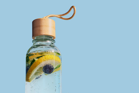Reusable glass bottle containing refreshing fruit water with lemon, cucumber and blueberries