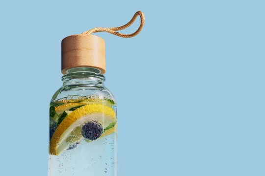 Reusable glass bottle containing refreshing fruit water with lemon, cucumber and blueberries