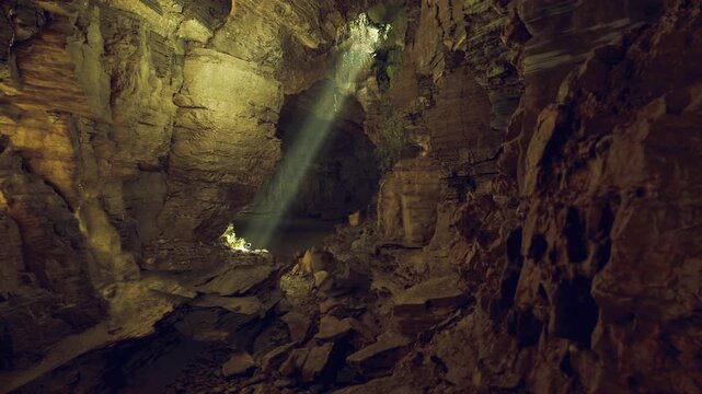 Towering chamber mammoth cave system illuminated by narrow light shaft, scattered rubble and textured walls emphasize scale and quiet solitude.