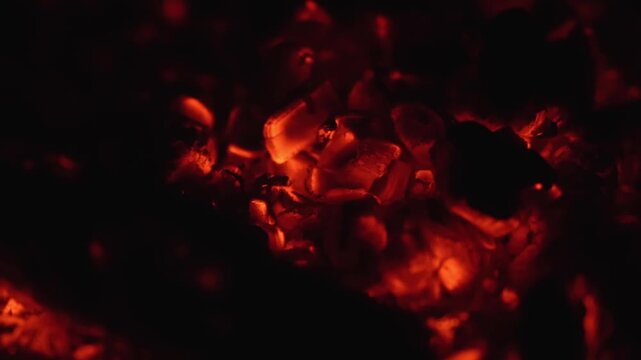 Macro shot of smoldering coals, illuminating textures and fading flames.