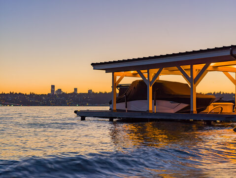 Boat dock with covered vessel at sunset over Washington city skyline