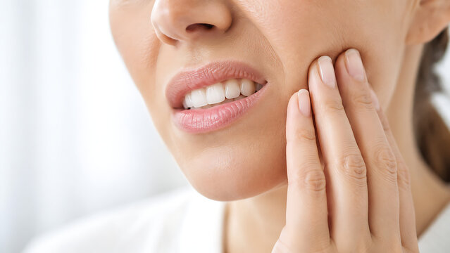 Close up of woman touching cheek with tooth pain, showing toothache, sensitive teeth, gum inflammation, dental infection, jaw discomfort and oral healthcare concept.