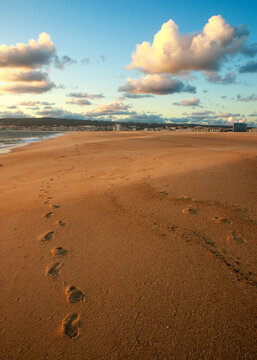 Incredible sunset over a wide ocean beach, on the background of a colourful, cloudy sky and the city