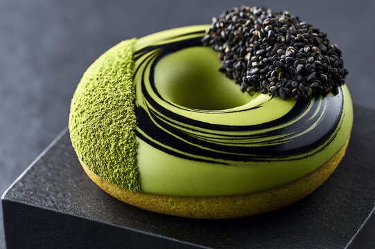 Close up of a gourmet matcha green tea donut with black sesame seed swirl