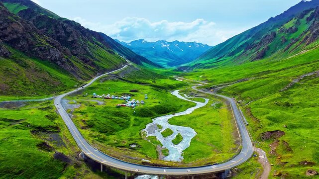 Scenic Duku highway winding through lush green mountain valley and river in Xinjiang, China.