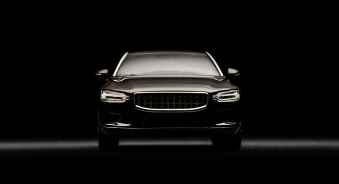 Front view of black miniature car in dramatic darkness.