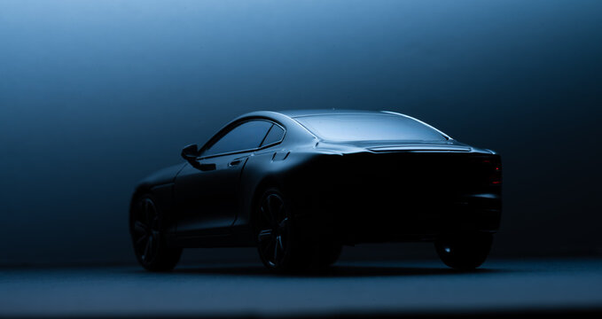 Dark miniature coupe model photographed with cool blue backlight.