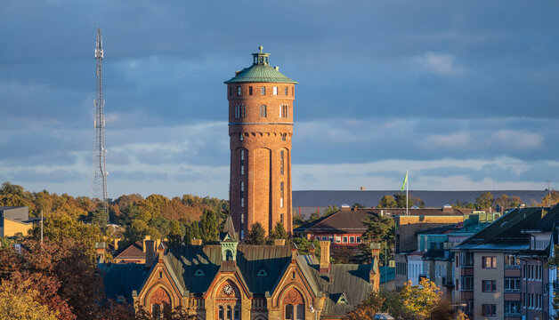 Historic brick tower above urban rooftops in dramatic autumn light.