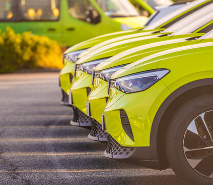 Bright green electric vehicles parked in neat commercial row.