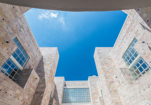 Modern stone courtyard architecture framing vivid blue sky.