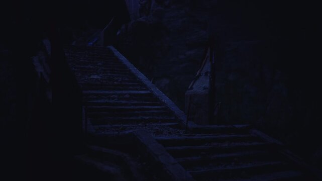 Concealed escape stair plunging into dark cavern, narrow passage framed by jagged rock and faint exit glow promising refuge or danger while tension fills frame.