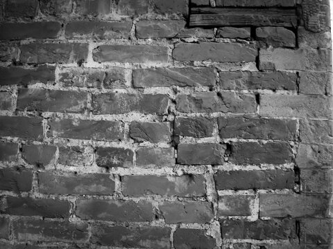 black-and-white texture of an old, weathered brick wall. aged brickwork with visible cracks, shadows, and remnants of plaster or mortar. grunge background