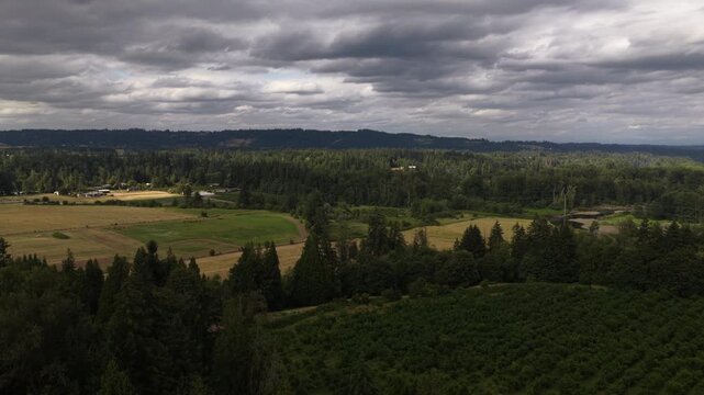 Summer aerial of rural Aurora Oregon landscape with dense forests and farmland with patches of cultivated fields and dark cloudy sky