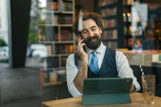 Bearded man multitasking with phone call and digital tablet