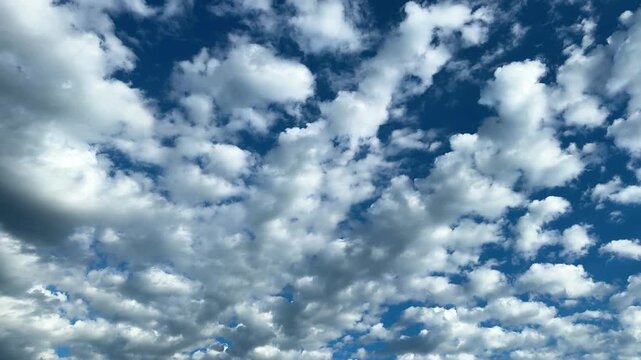 White and gray clouds scattered across blue sky. Fluffy cumulus cloud formations in daytime sky, natural weather pattern, atmospheric background