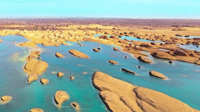 Aerial view of the unique water yardang landform with golden sand dunes and turquoise blue lake in Qinghai, China.