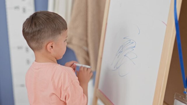 Boy drawing on a whiteboard easel with blue marker, hand raised, scribbling loose lines on the board in studio; curiosity creativity learning.