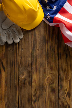 Labor Day in USA honoring American worker with hardhat, gloves and flag on vertical wood background