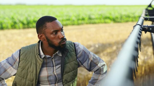 Concerned farmer standing beside a combine harvester after a mechanical issue, representing equipment breakdown, harvest delays, agricultural challenges and farm management.