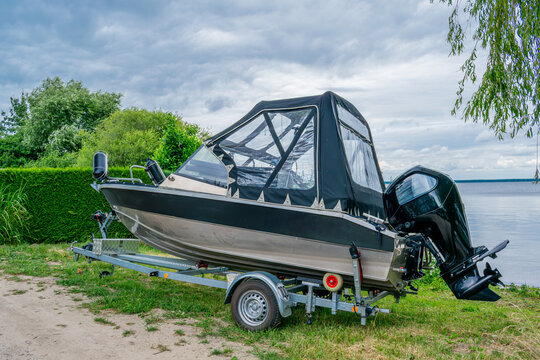 Motorboat with a black canvas bimini top on a trailer parked by the lake