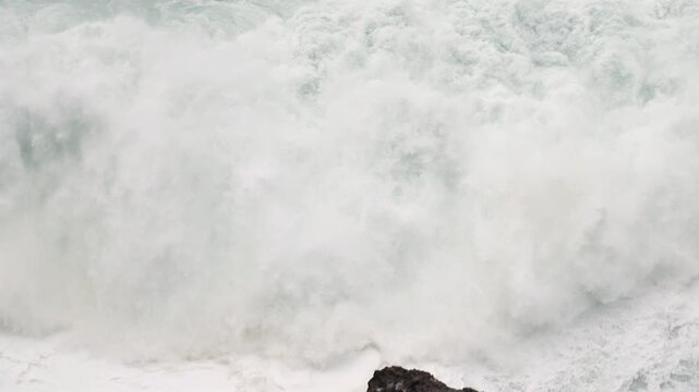Giant Atlantic waves roll into Nazare shoreline, Portugal. Ocean Wave Foam in Slow Motion. Storm swell.
