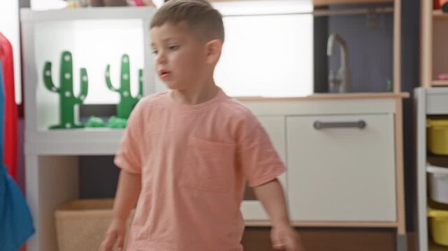 Boy hispanic little playing with wooden toy cars and train track, hand guiding vehicles on floor inside children's playroom building; concentration.