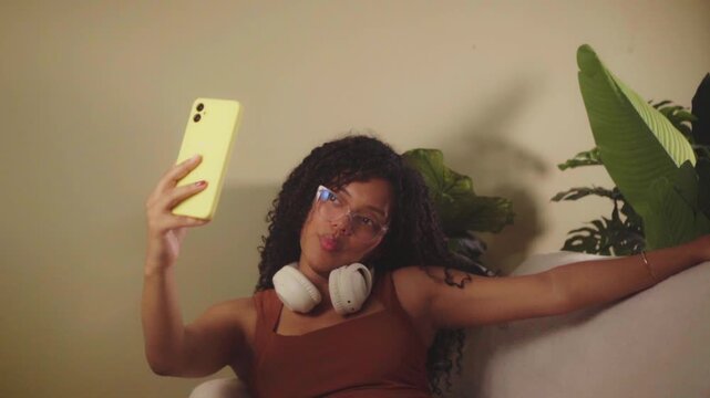 Young hispanic woman relaxing and taking a selfie